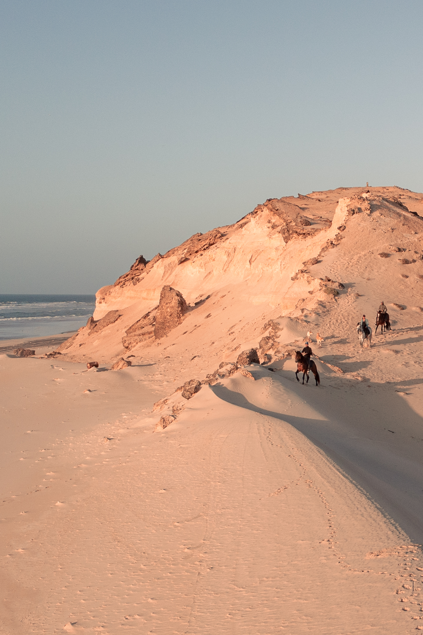Drone view of riders along the beach between dunes and ocean in Dakhla